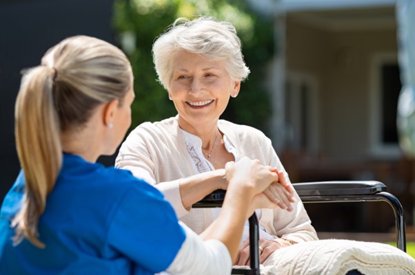 A smiling elderly woman holds hands with a caregiver outdoors, capturing the warmth and trust that define home care franchise success in Alabama’s culture of Southern hospitality.