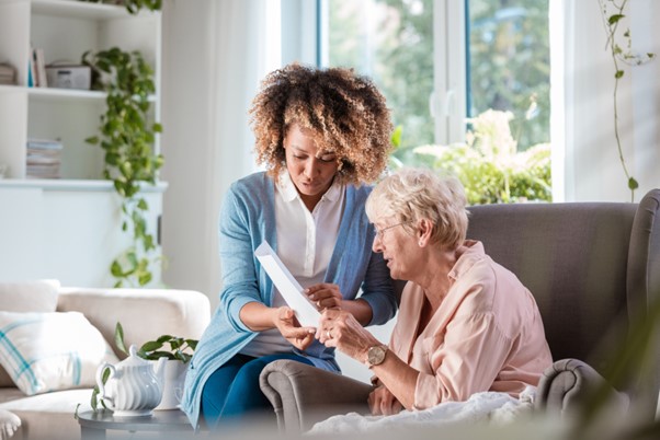 A caregiver attentively explains information to a senior woman in a cozy living room, reflecting the trust and support that home care franchises provide to families in New Jersey.