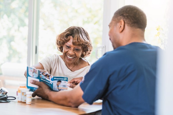 A smiling senior woman and a caregiver review a health brochure together, symbolizing the personalized, holistic home care services embraced by Oregon’s wellness-focused senior community.
