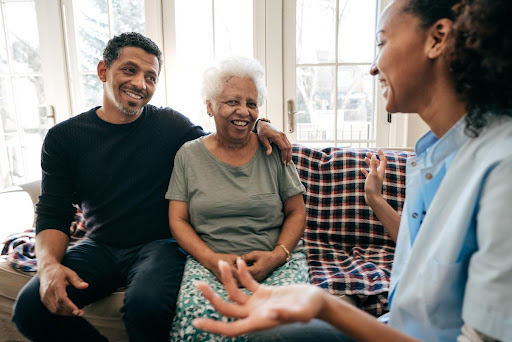 A cheerful family consults with a home care professional in a bright living room, representing the personal and financial benefits—and stronger ROI—of choosing a franchise model over an independent home care startup.