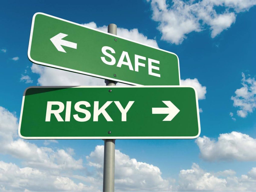 Green road signs pointing in opposite directions labeled Safe and Risky, symbolizing the choices and uncertainties of franchising.