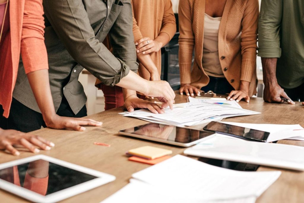 Team gathered around a table reviewing charts and marketing plans, symbolizing how franchise owners can succeed even without strong sales skills through professional support.
