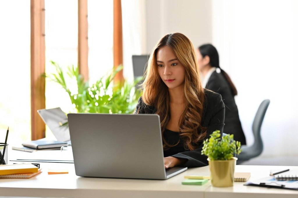 Professional woman working on a laptop in a modern office, representing a corporate executive transitioning to a purpose-driven home care franchise.