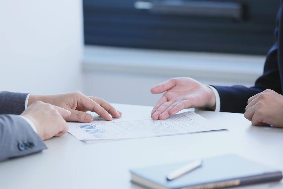 Two business professionals reviewing and discussing a document at a desk, representing the details and implications of a franchise agreement.