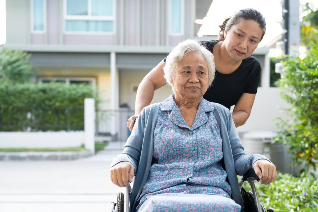 Caregiver assisting an elderly woman in a wheelchair outside a home, symbolizing how compassion and dedication—rather than prior experience