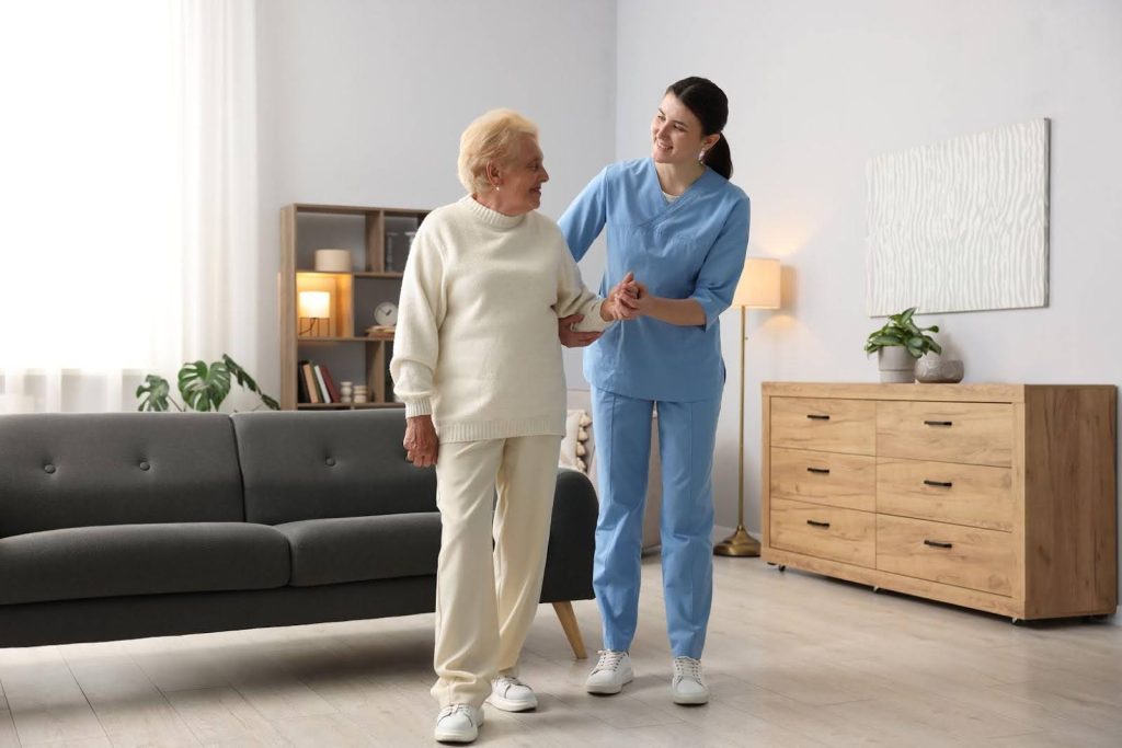 Caregiver supporting an elderly woman while walking indoors, symbolizing a mission-driven franchise focused on compassionate and scalable care.