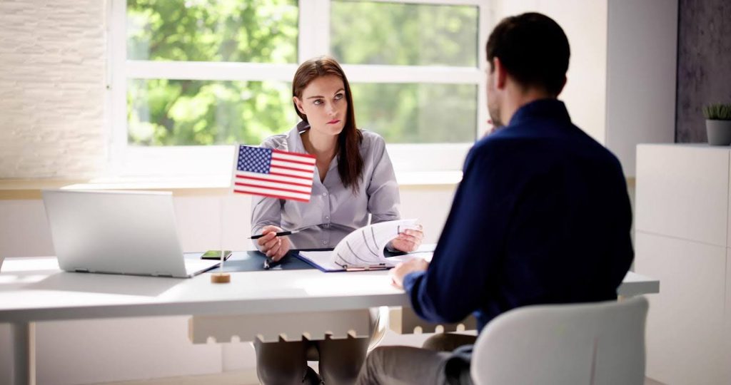 Person meeting with a U.S. immigration officer, representing professionals immigrating to start purpose-driven senior care businesses through the E2 visa program.