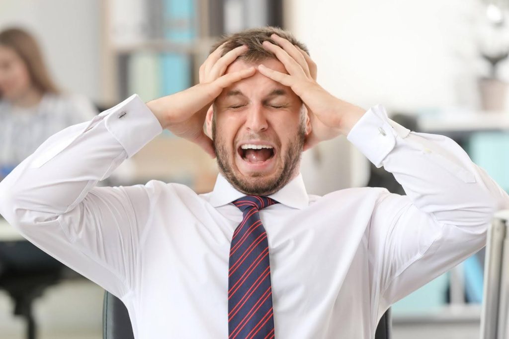 Stressed businessman holding his head in frustration, symbolizing the common fears and challenges new franchisees face when starting their business.
