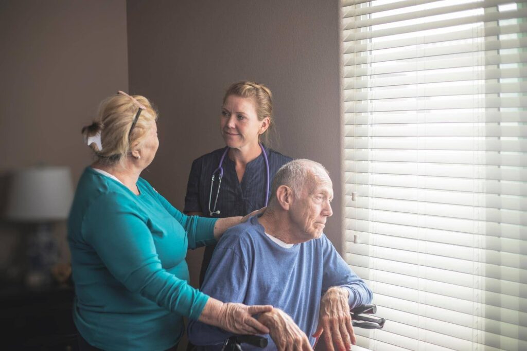 Caregiver supporting elderly couple at home representing the work behind a successful home care business by Ace Home Care Franchise
