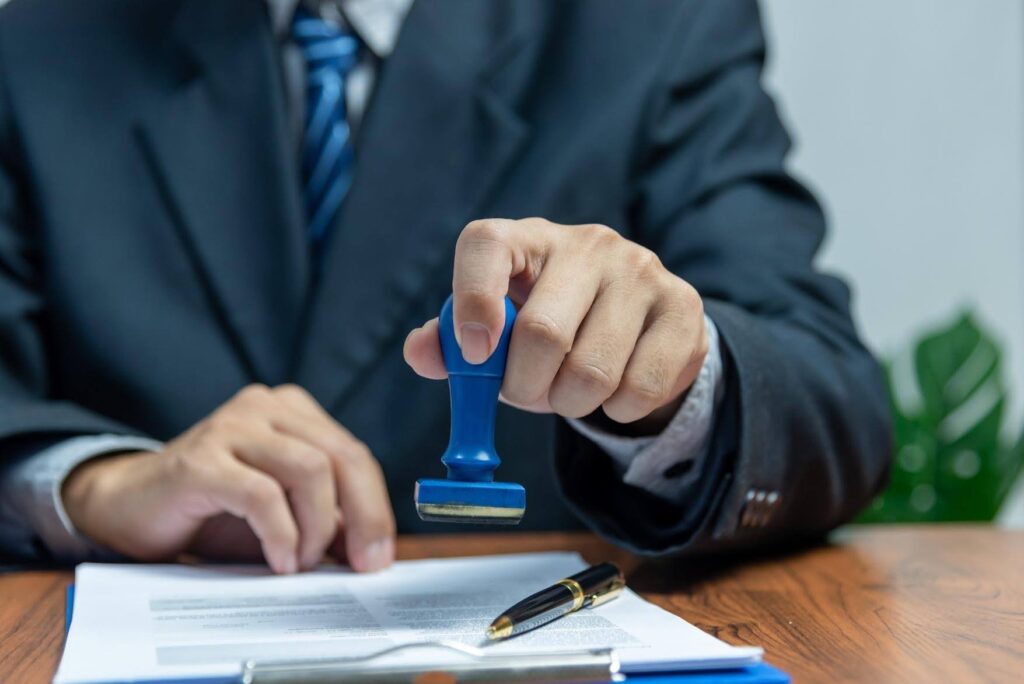 Business professional stamping official documents, representing the process to qualify for an E-2 Visa through an Ace Home Care Franchise investment