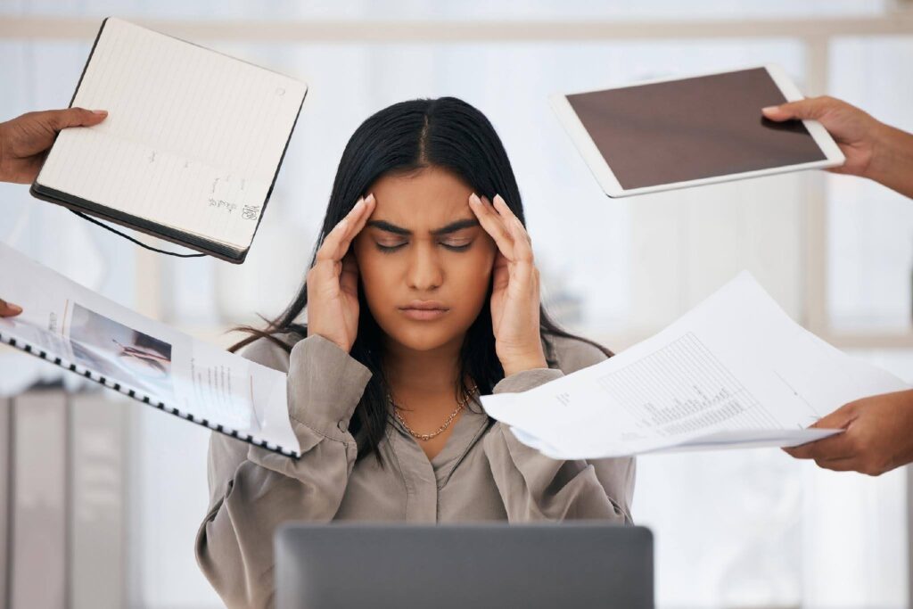 Professional experiencing job burnout while managing multiple work demands, representing how Ace Home Care Franchise helps entrepreneurs transition from employee to business owner