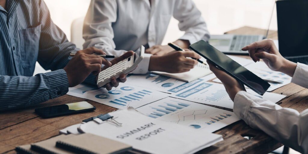 Business professionals reviewing financial documents and calculating SBA franchise loan costs for an Ace Home Care Franchise investment opportunity.