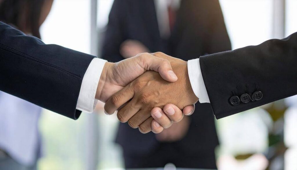 Business professionals shaking hands during a franchise agreement meeting, highlighting the important questions to ask before investing in an Ace Home Care Franchise opportunity.