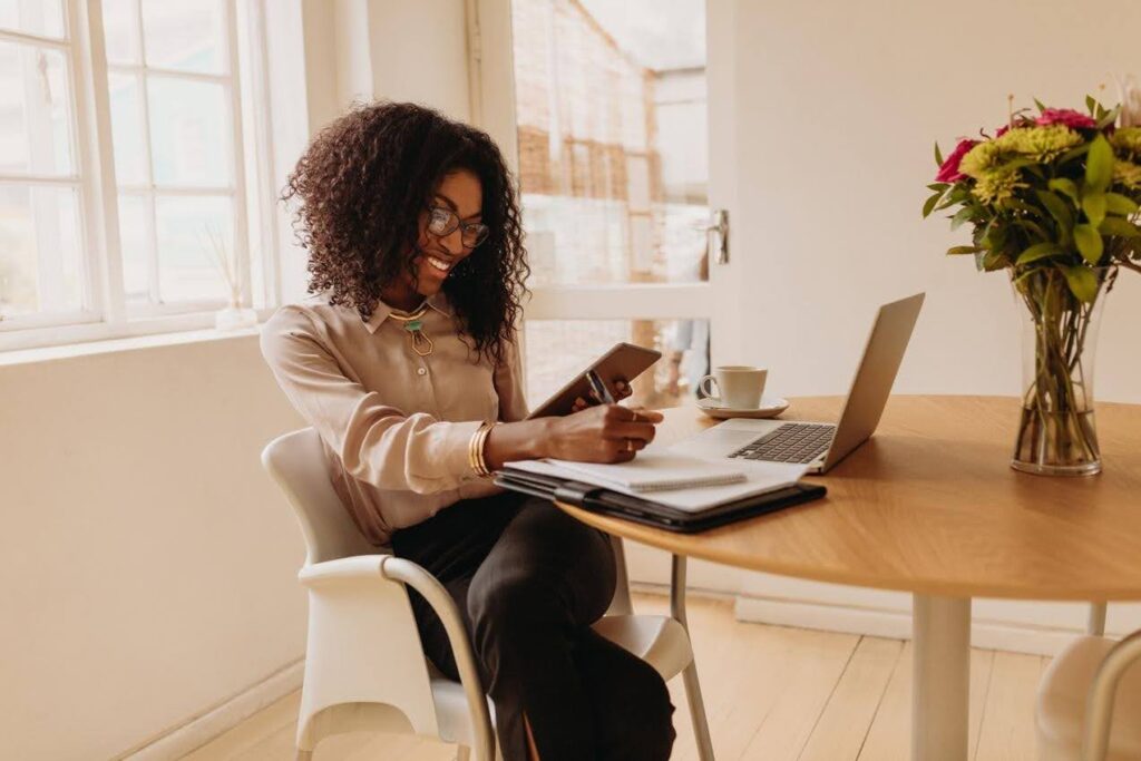 Entrepreneur managing an Ace Home Care Franchise remotely using a laptop and tablet, demonstrating how to successfully run a home care business from anywhere.